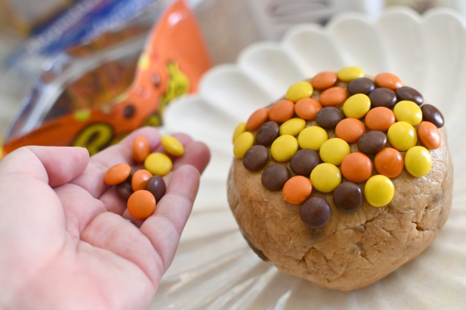 placing Reese's Pieces on a peanut butter cheese ball