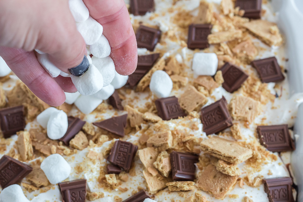 putting marshmallows on top of smores lasagna 