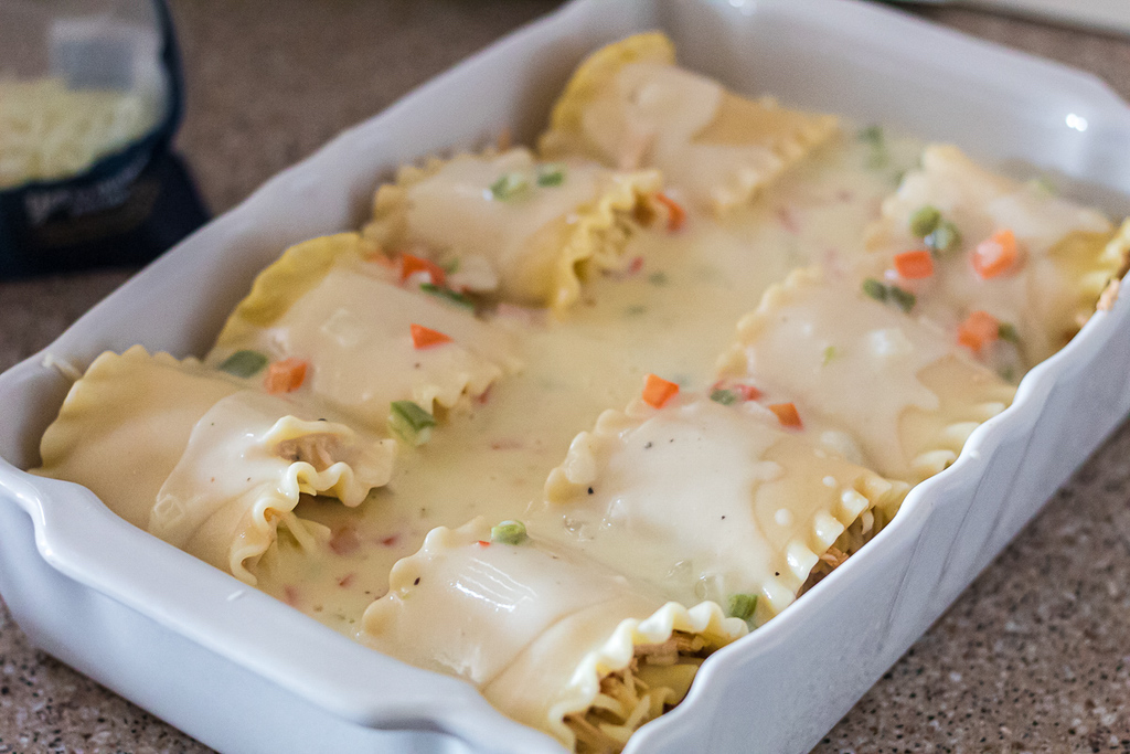 spicy chicken lasagna roll-ups with creamy sauce in casserole dish