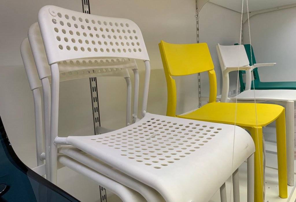 white chairs with holes stacked on store shelf