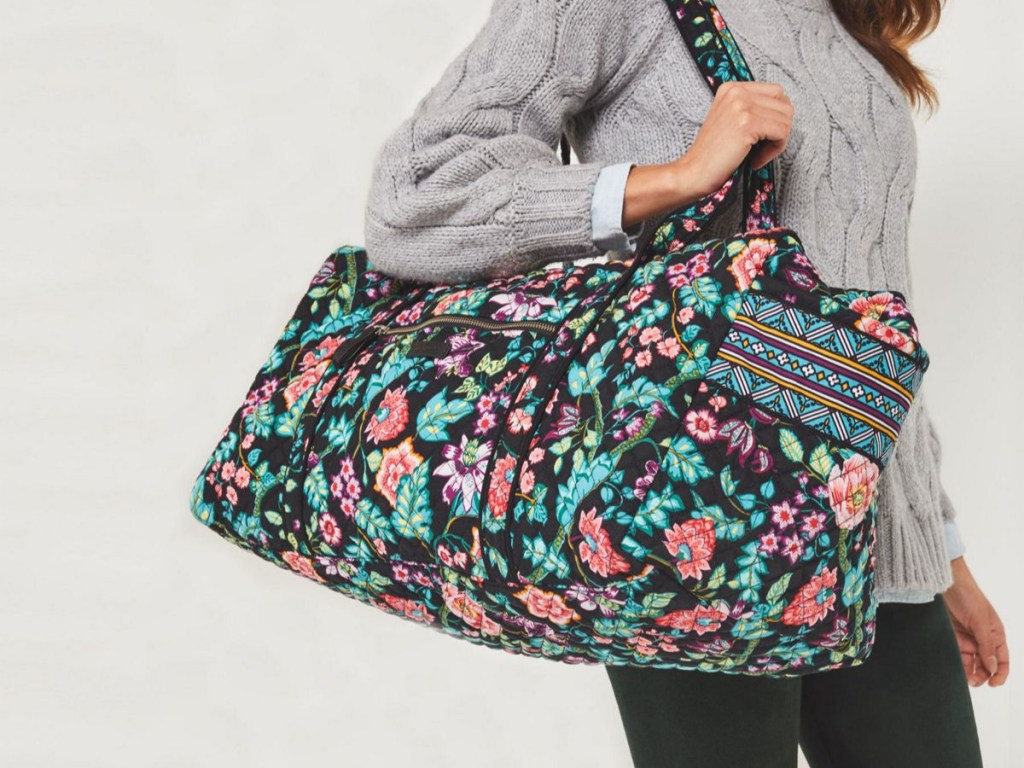 woman modeling duffel flowered bag