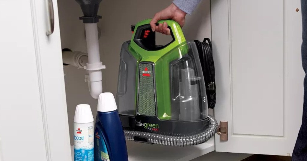 BISSELL Little Green ProHeat Portable Deep Cleaner being put away under the cabinet