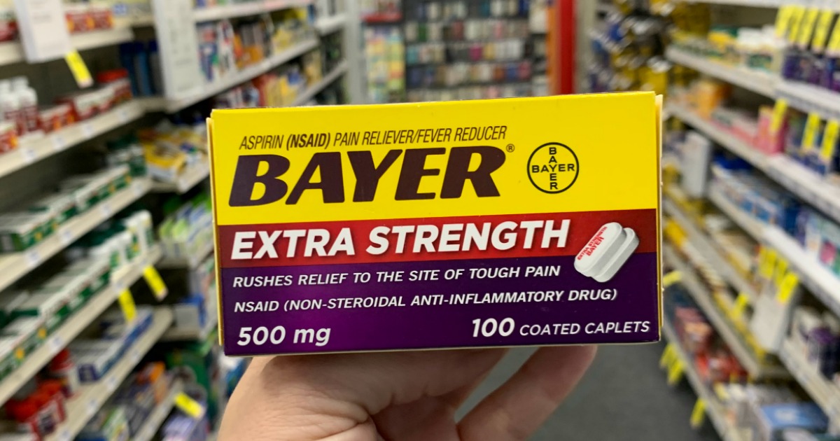 Hand holding Bayer in front of shelf 