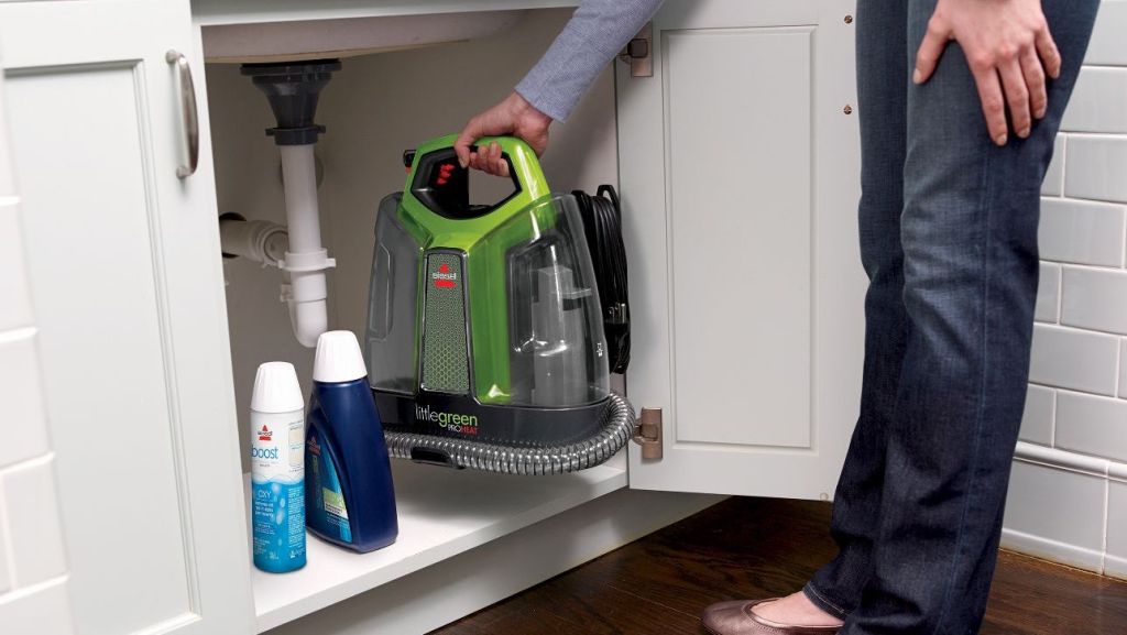 woman putting Bissell ProHeat Cleaner under counter