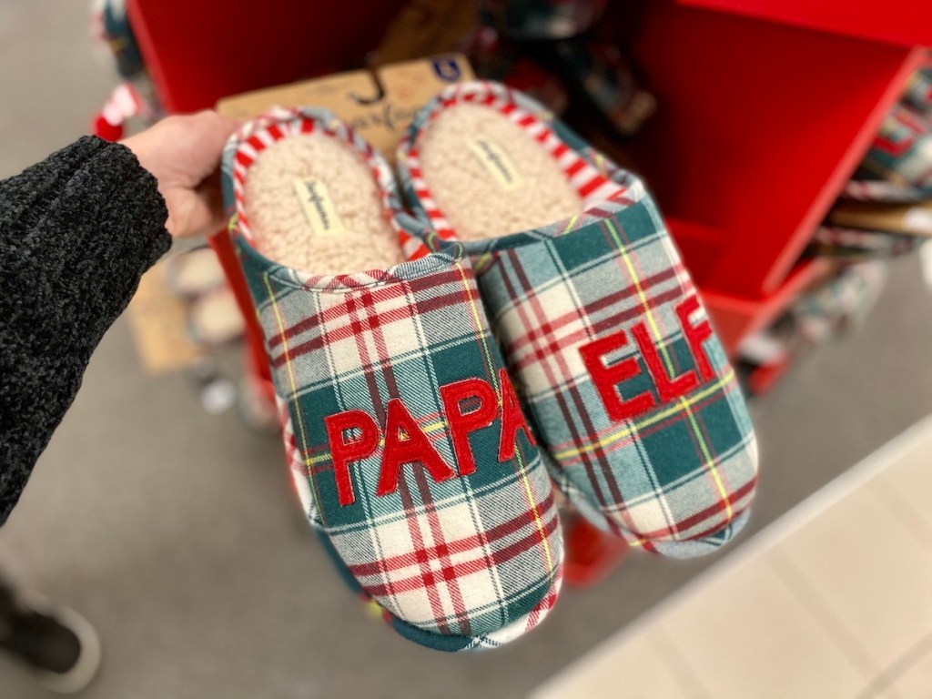 Woman holding pair of Dearfoams Men's Matching "Papa Elf" Slippers