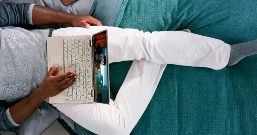 man using laptop while laying in bed