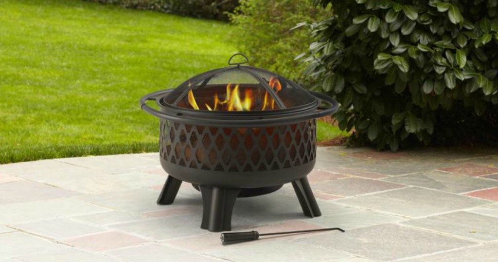 small fire pit on sidewalk in a backyard setting