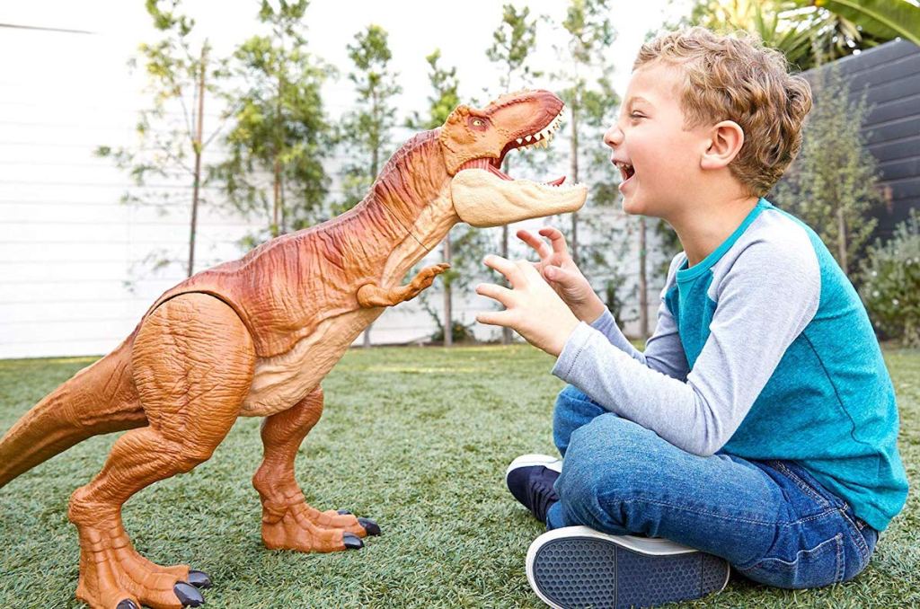 boy playing with Jurassic World Super Colossal Tyrannosaurus Rex in backyard on grass