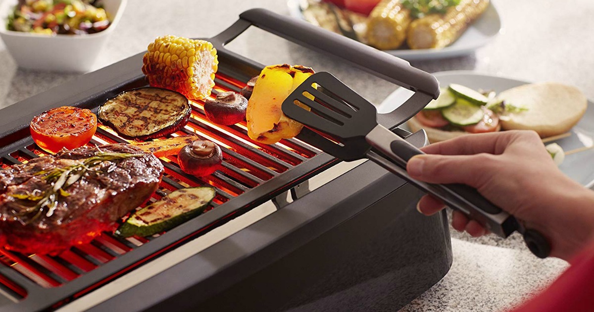 person using tongs to turn vegetables on Philips smokeless grill