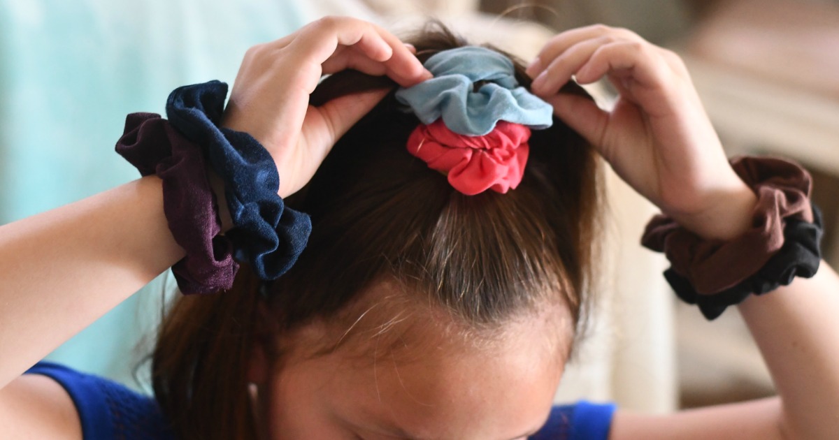 Girl wearing a stack of velvet hair scrunchies on her head and wrists