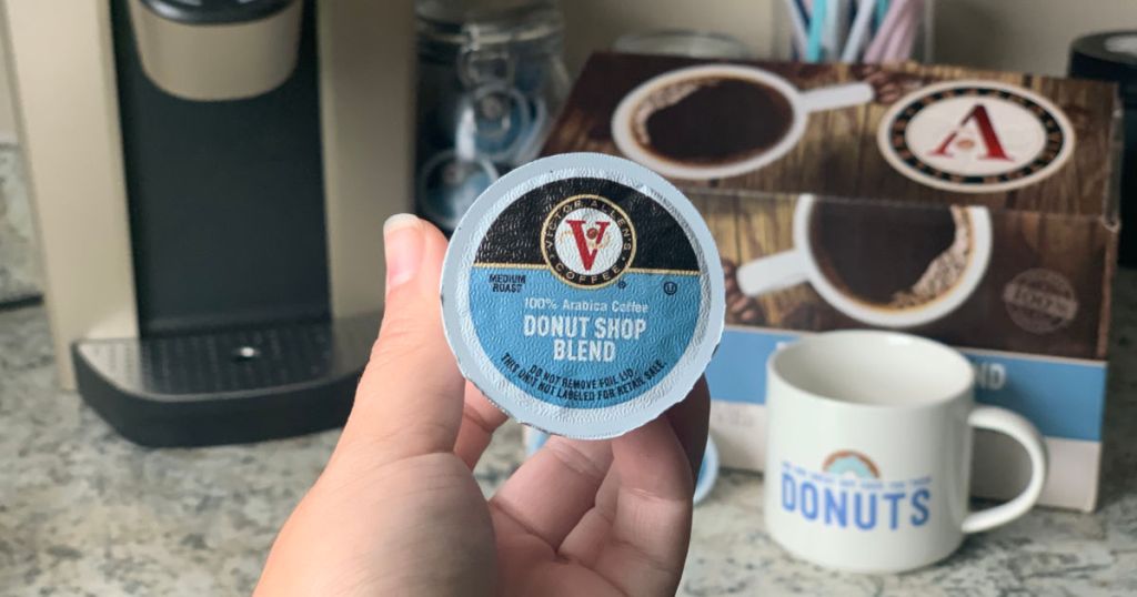 woman hand holding Victor Allen Donut Shop K-Cup in the kitchen with Keurig coffee maker and donut coffee mug