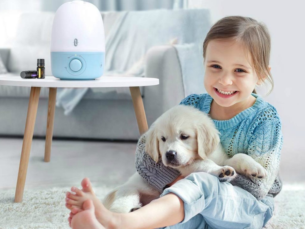 Baby whale humidifier on a side table next to a girl holding a dog