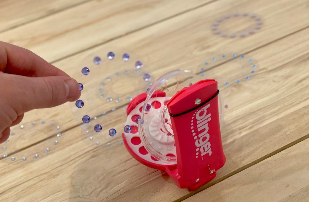 hang holding hot pink blinger gems on table 