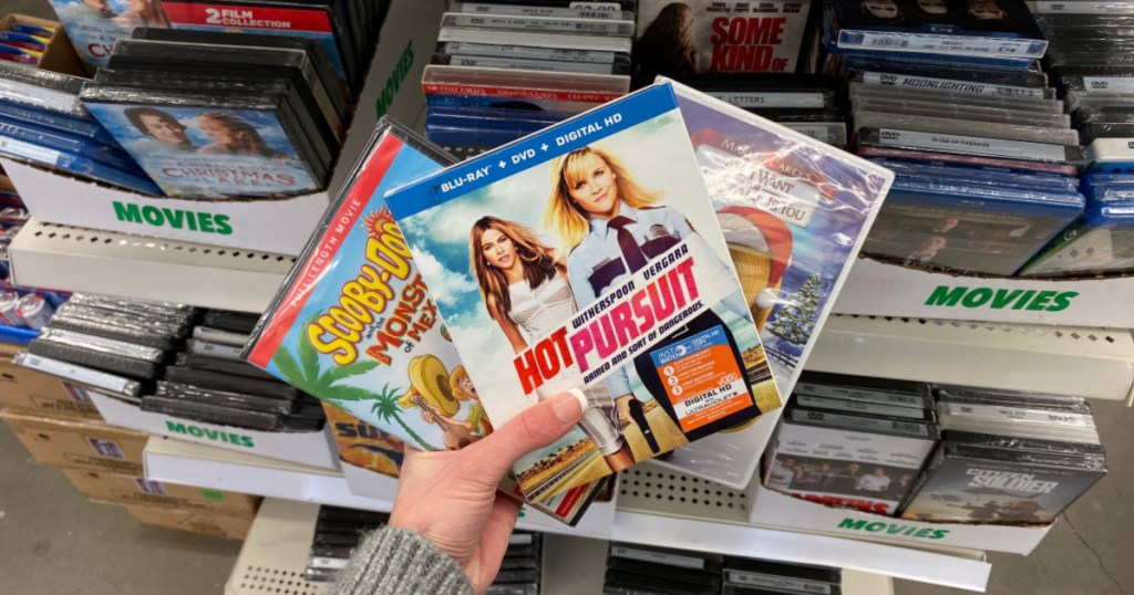 hand holding up 3 movies at dollar tree