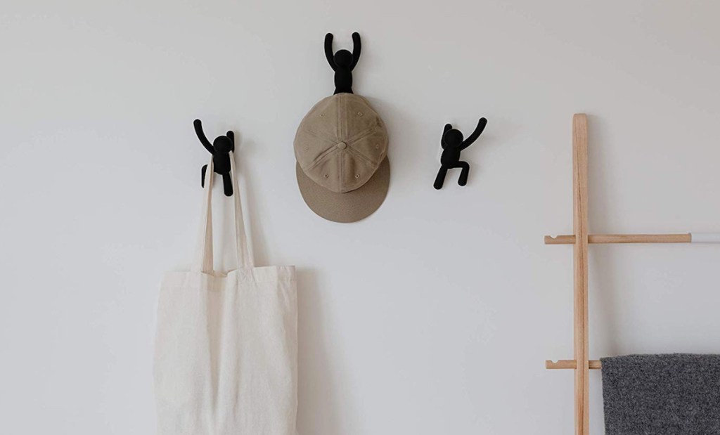 black decorative buddy wall hooks on wall with hat and bag