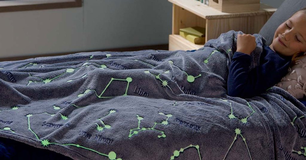 little girl sleeping in bed under constellation glow in the dark throw 