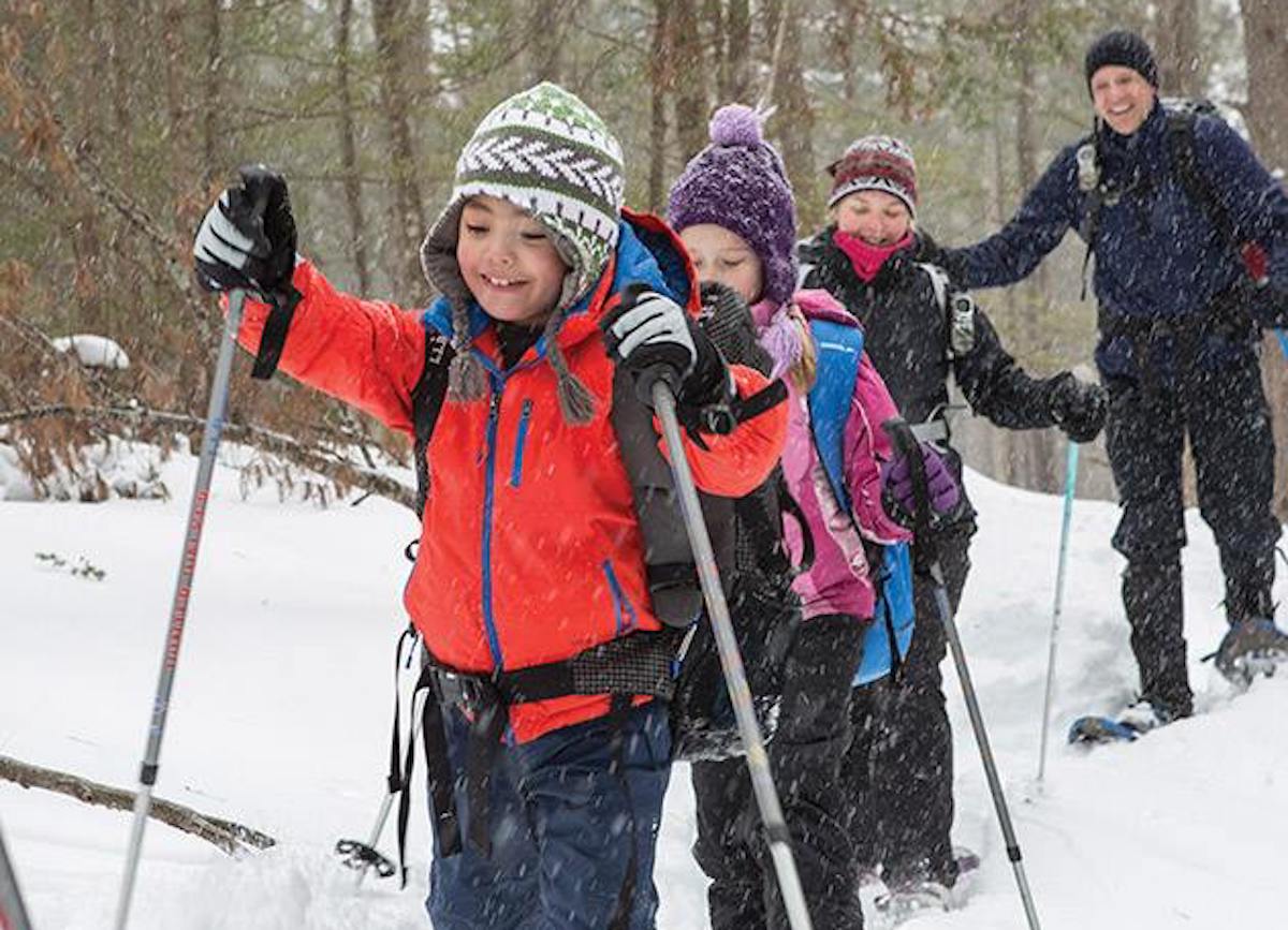 kids walking through snow with skis