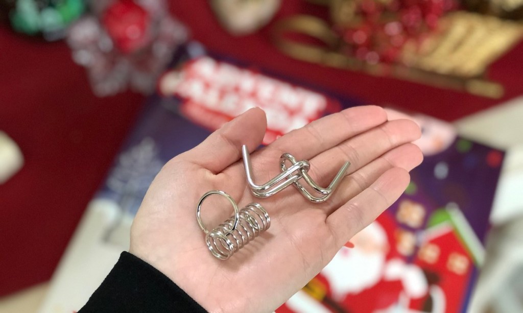 hand holding two metal puzzles with advent calendar in background 