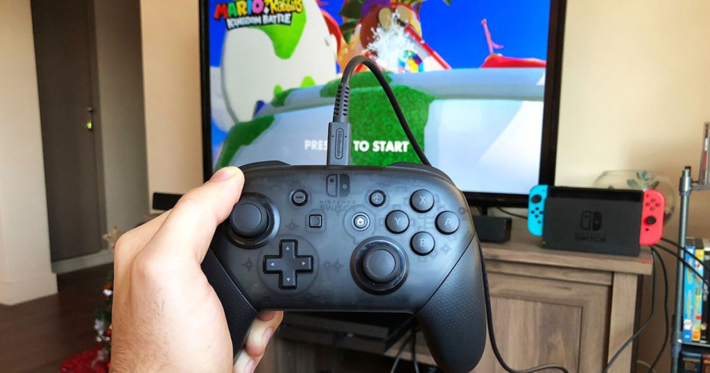 hand holding PowerA Controller for Nintendo Switch in front of tv