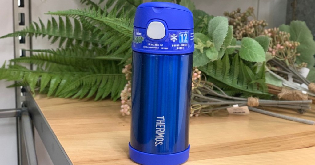 blue thermos sitting on counter with flowers in background