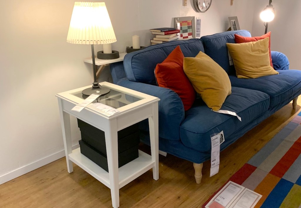 white side table next to blue couch and light lamp on top 