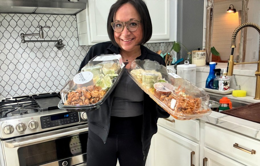 woman holding a costco premade meal and sam's club premade meal 