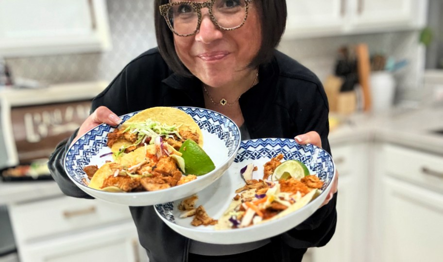 woman holding a plate of tacos