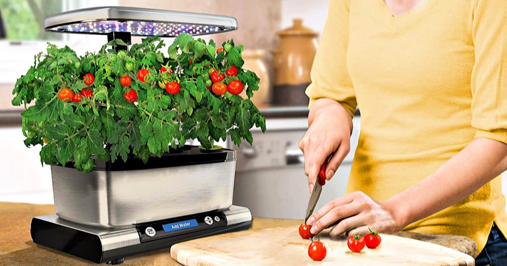 AeroGarden Harvest Elite on kitchen counter with woman cutting tomatos