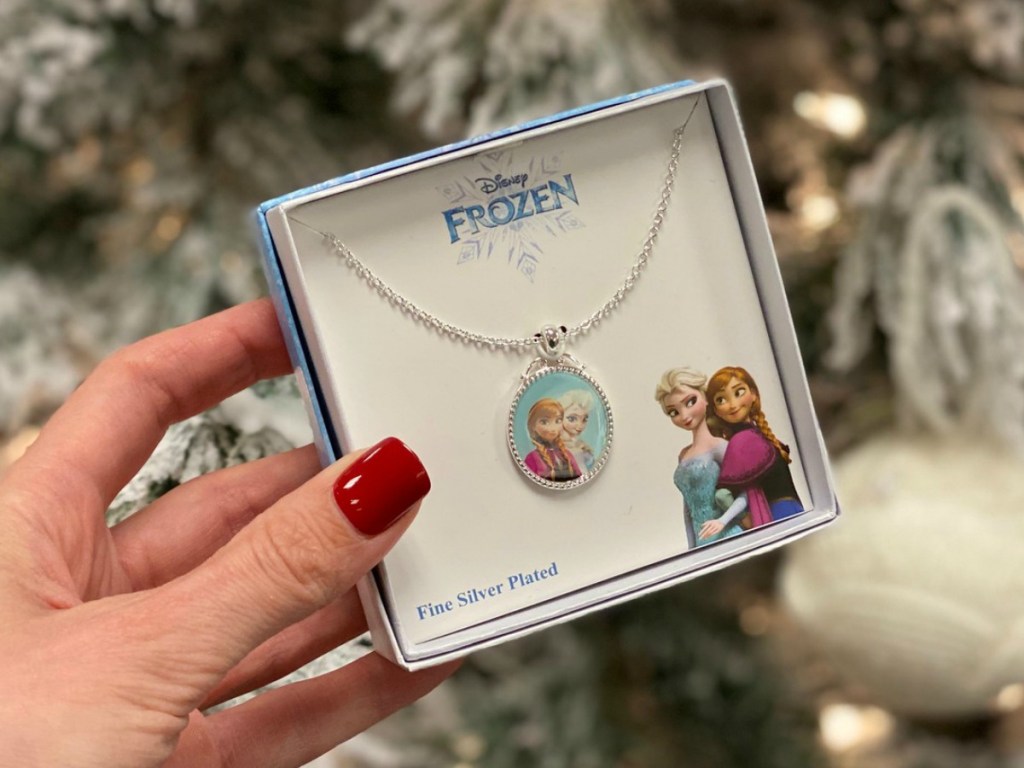 Disney Frozen 2 Sister Pendant in gift box in hand near Christmas tree