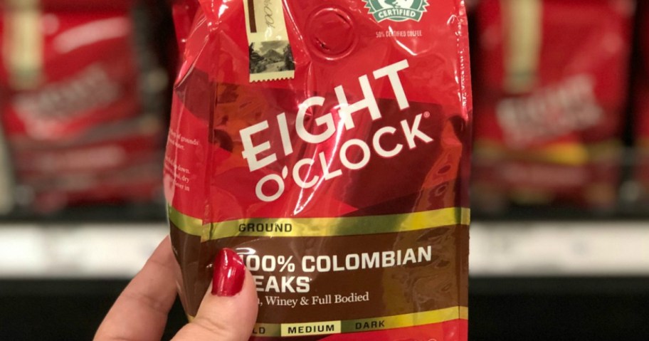 Woman holding a bag of Eight O' Clock brand coffee in package in-store