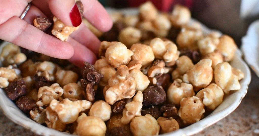 woman reaching for caramel popcorn and chocolate mix