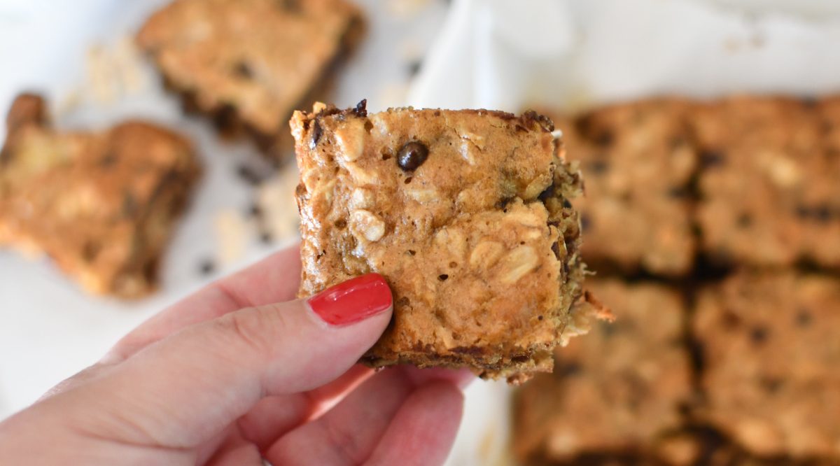 Hand holding up an easy oatmeal square made with chocolate chips