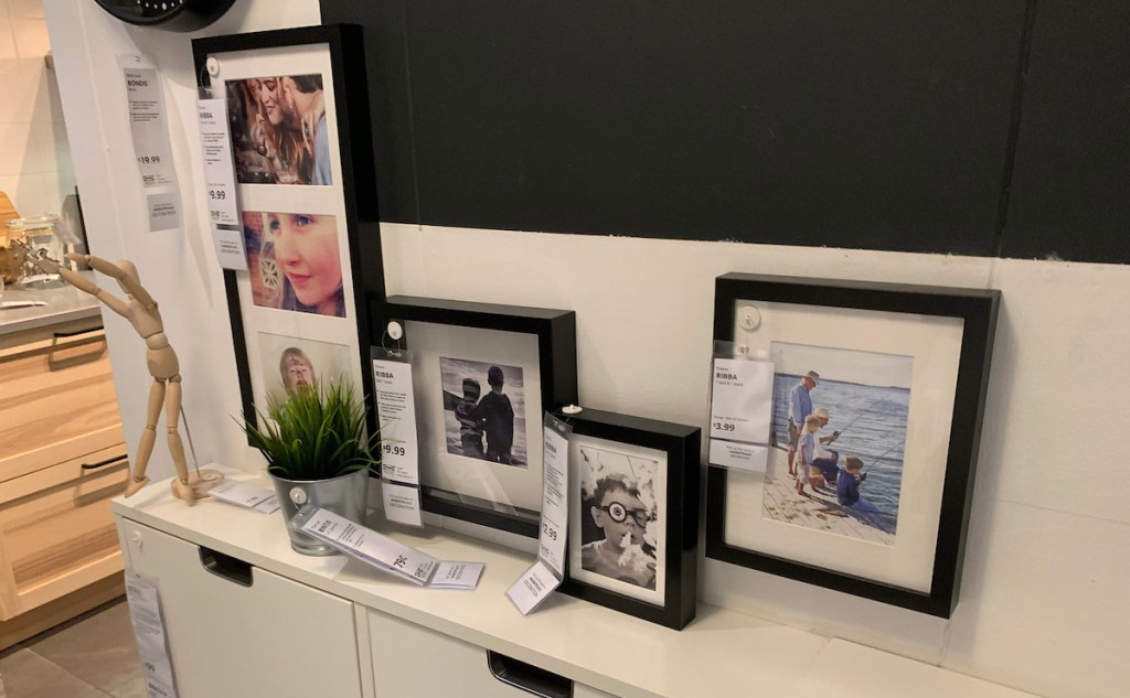 various sizes of black picture frames sitting on white console table 