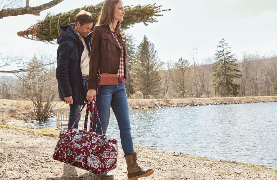 woman carrying a Vera Bradley Duffel bag and man carrying a tree