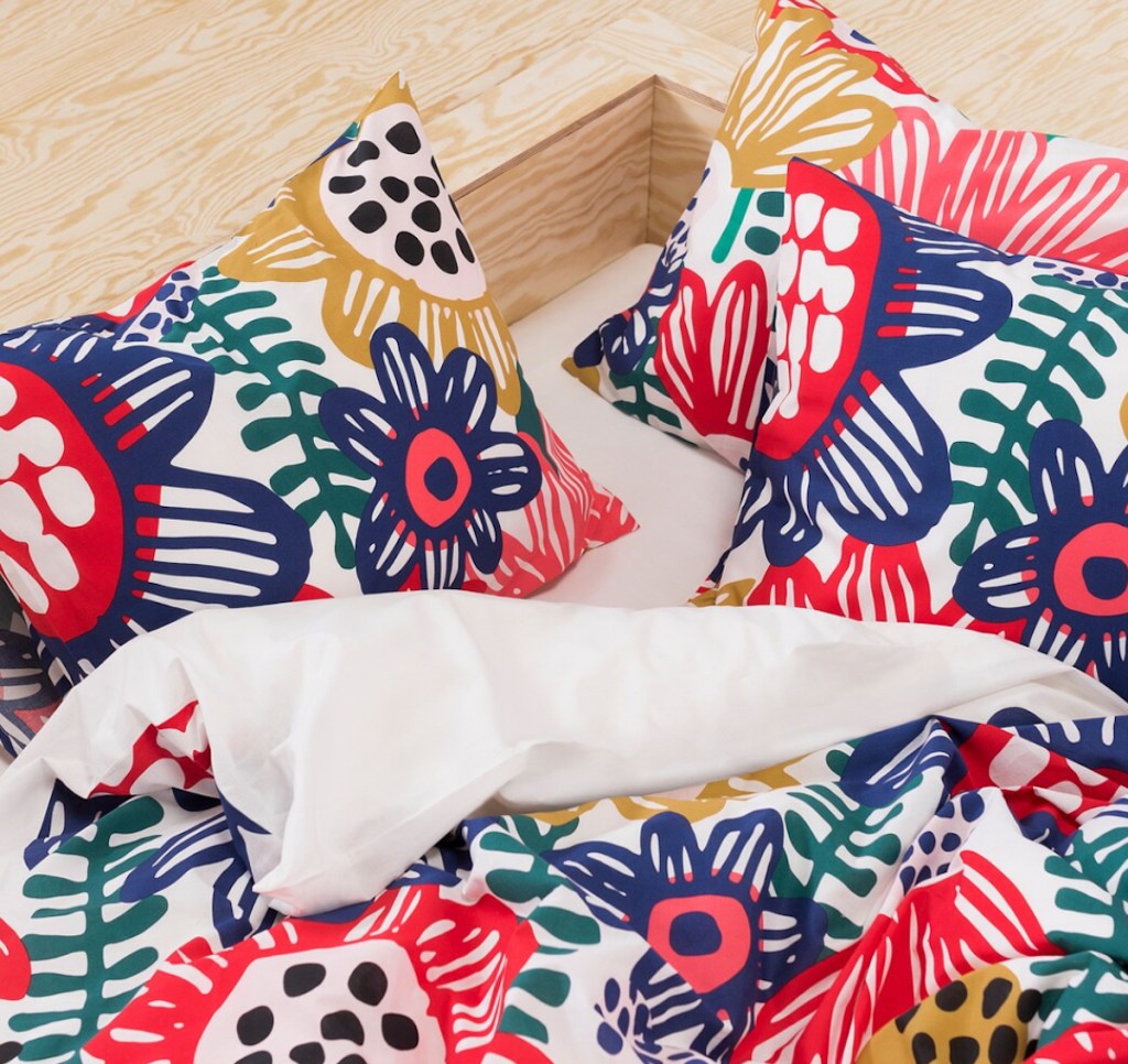 colorful floral bedding and pillows with wood floor in background