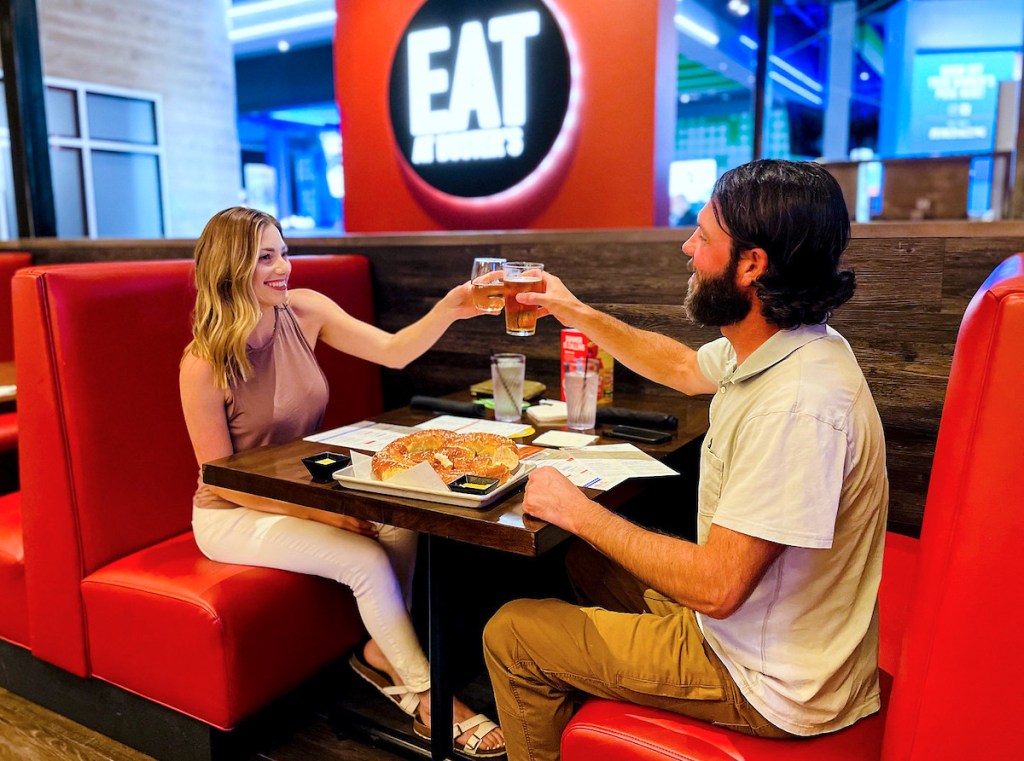 couple holding up drinks for a cheers in dave and busters booth