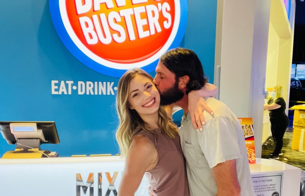 man kissing womans cheek with dave and busters sign in background