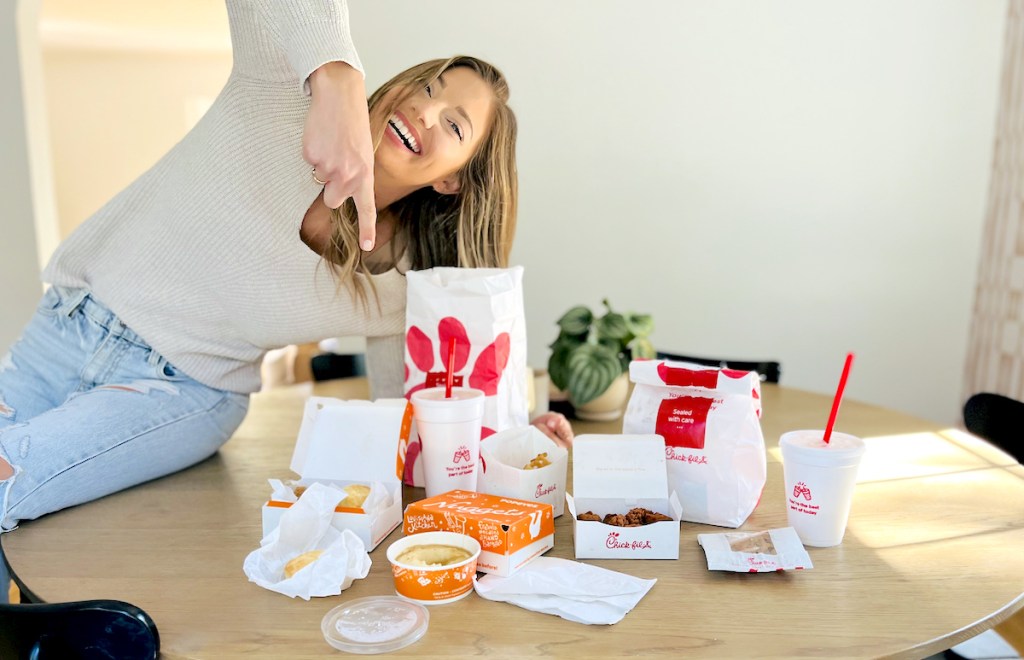 woman sitting on table pointing to best food delivery service 