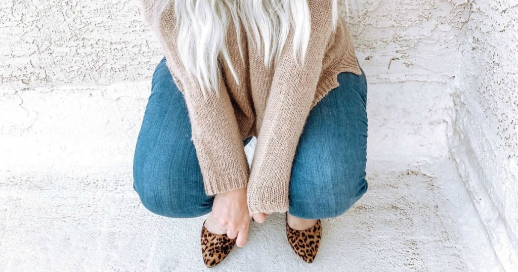 woman kneeling down wearing jeans and sweater 