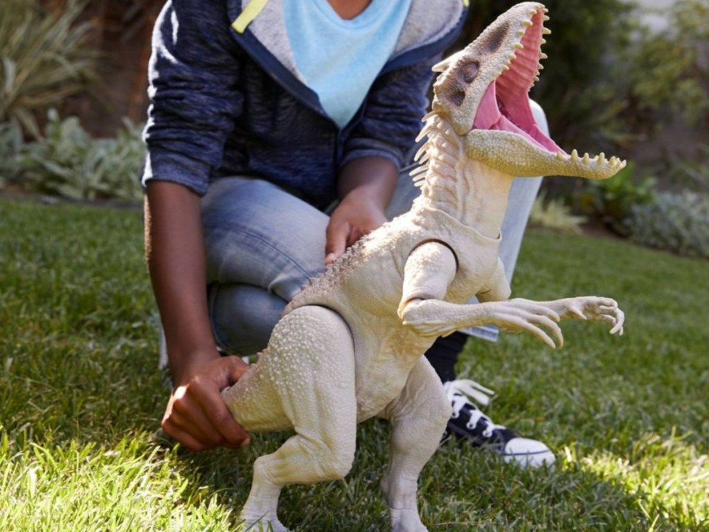 boy playing with dinosaur in yard