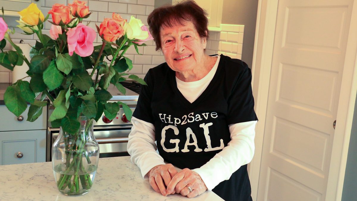 woman in kitchen next to vase of flowers