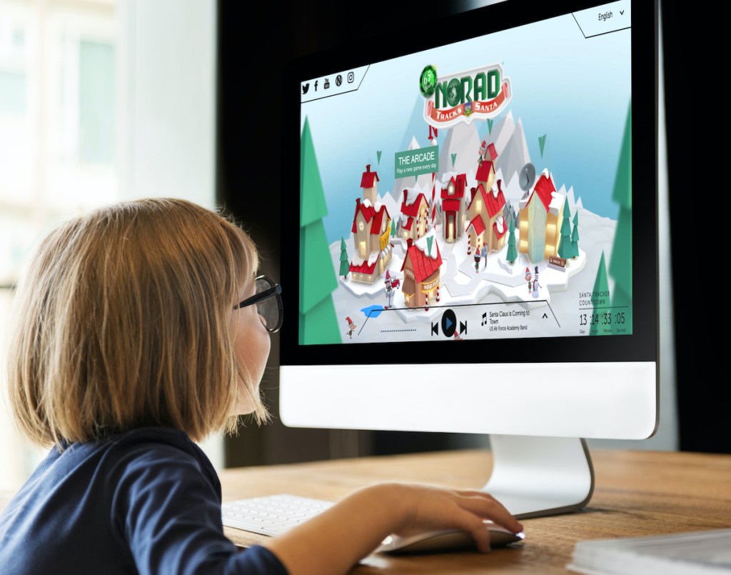 little girl sitting in front of the norad santa tracker virtual north pole on onlineputer screen