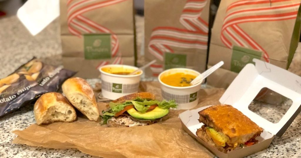 various sandwiches and soup with panera bags sitting on kitchen counter