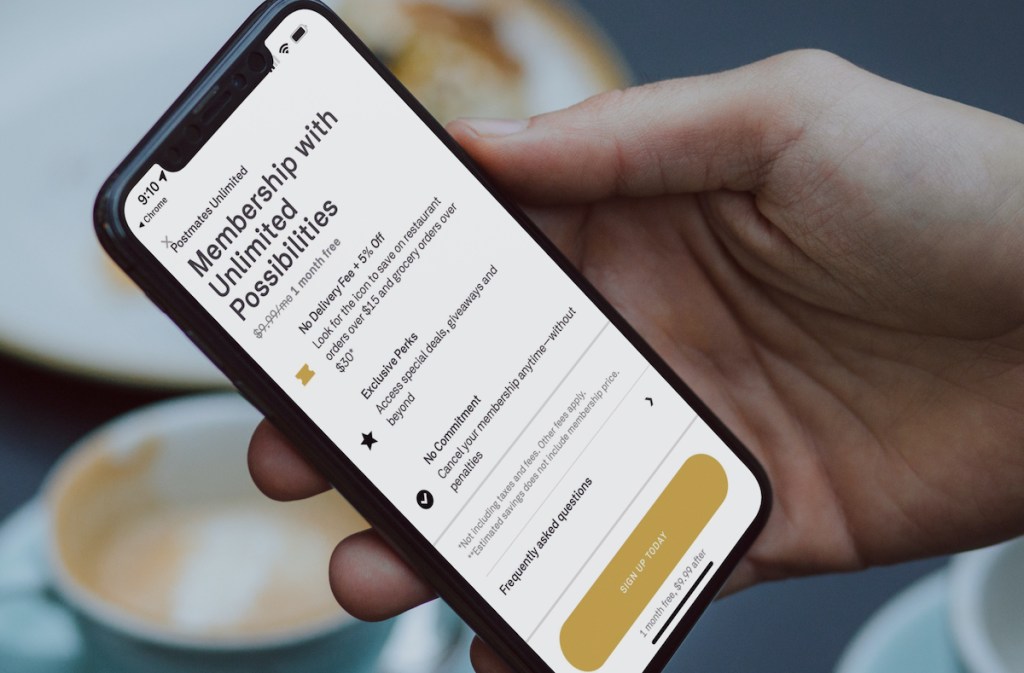hand holding a phone with postmates unlimited on screen
