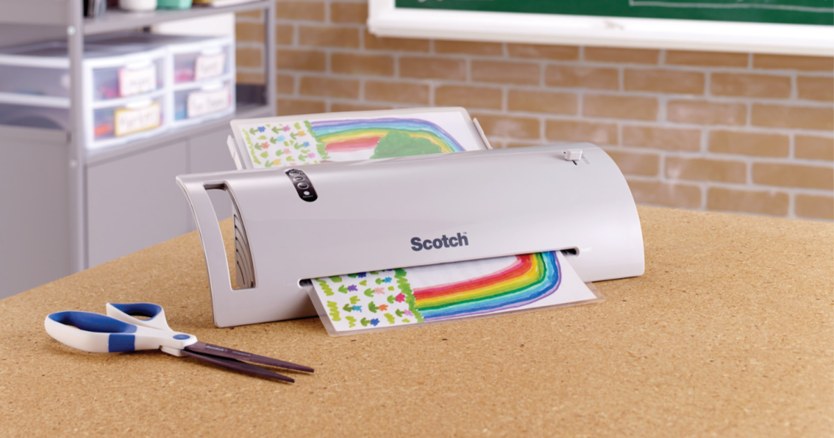 Scotch Thermal Laminator on table with scissors and paper being laminated