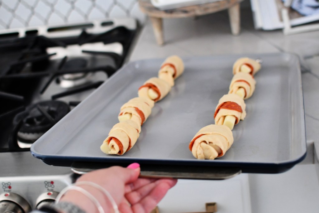 sheet pan with rolled up pizza crescents ready for the oven