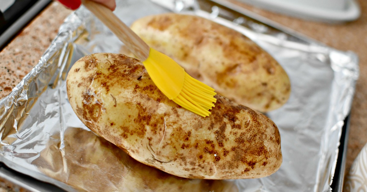 brushing olive oil on a baked potato