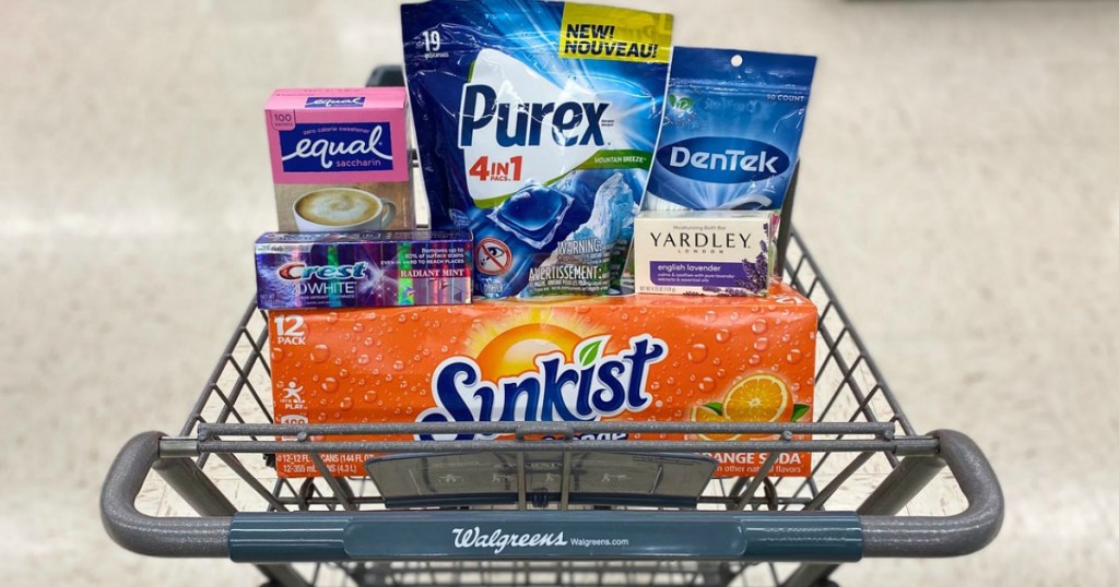 artificial sweetner, toothpaste, laundry pacs, flossers, bar soap, and 12-pack soda cans in a shopping cart in a store