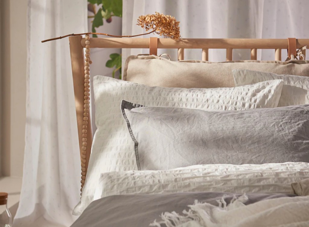 stock photo of wood bed with white and gray bedding on it