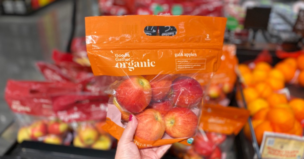 hand holding organic apples in store with apples in background